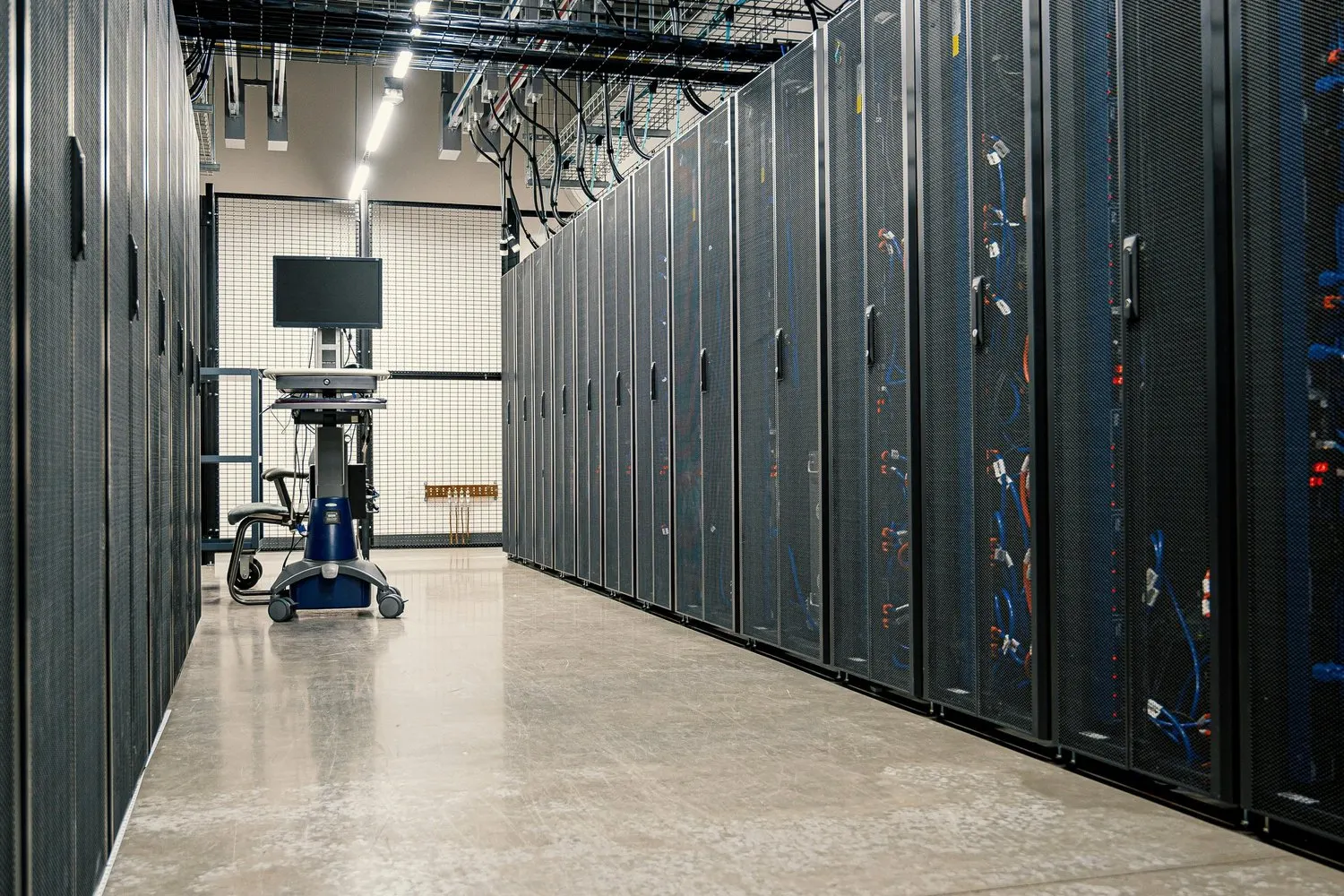 Aisle of server racks in a data center, with overhead cable trays